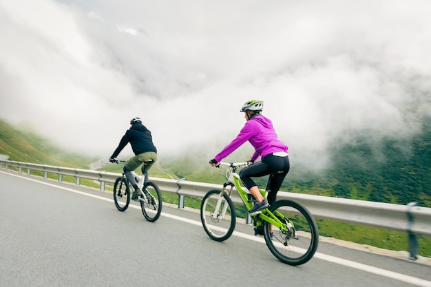 People riding bicycle on road against cloudy sky
