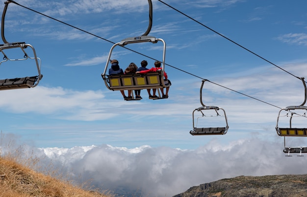 Photo people riding ski station chairlifts, watching the mountains and the horizon, back