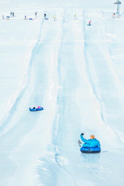 People riding snow tubing at winter park copy space