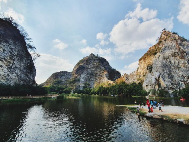 People on rock by lake against sky