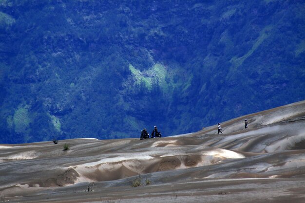 People on rock formation in desert against sky