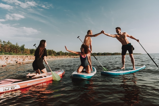 People Rowing Surfs In Sea With Paddles.