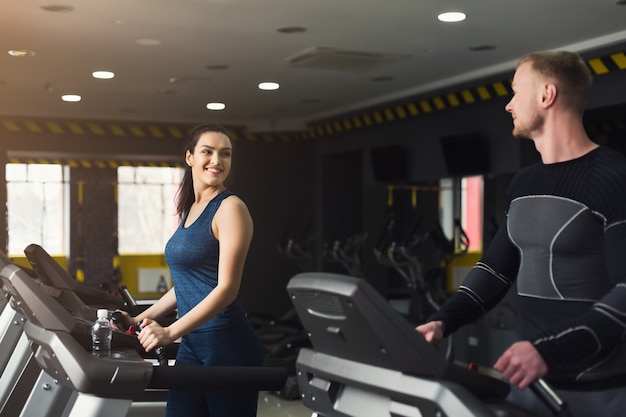 People run on treadmills. Men and women cardio workout in fitness club. Healthy lifestyle, training in gym, copy space