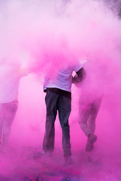 Photo people running amidst pink powder paint in city