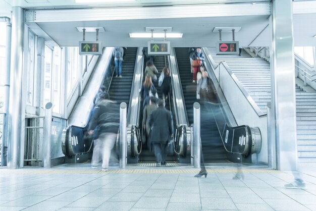 エスカレーターのモーションがぼやけて人々が急いでいる