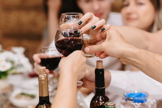 People's hands clink glasses with alcoholic beverages at a holiday in a restaurant