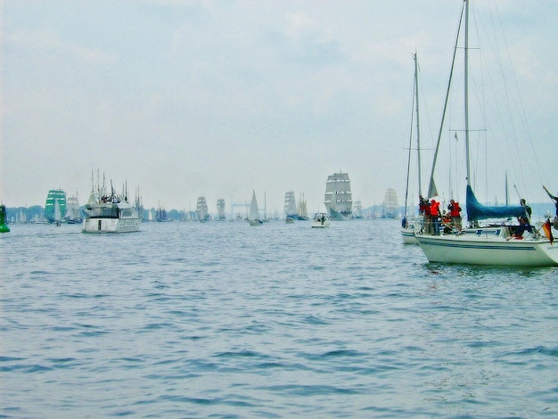 People in sailboat sailing on sea against sky