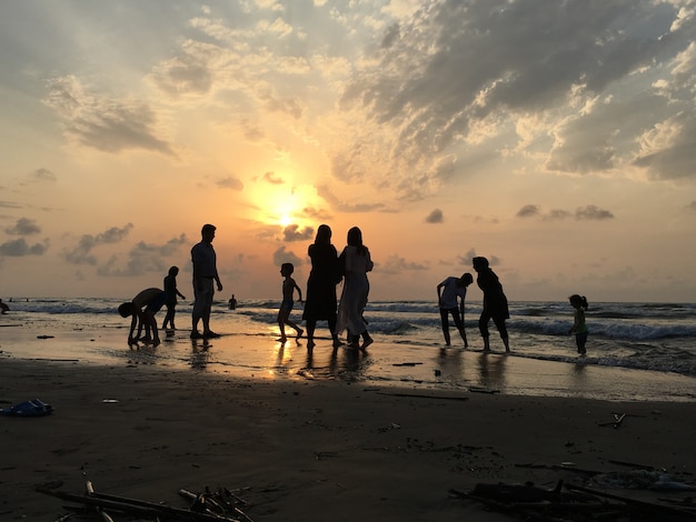 People on sea beach at sunset having fun