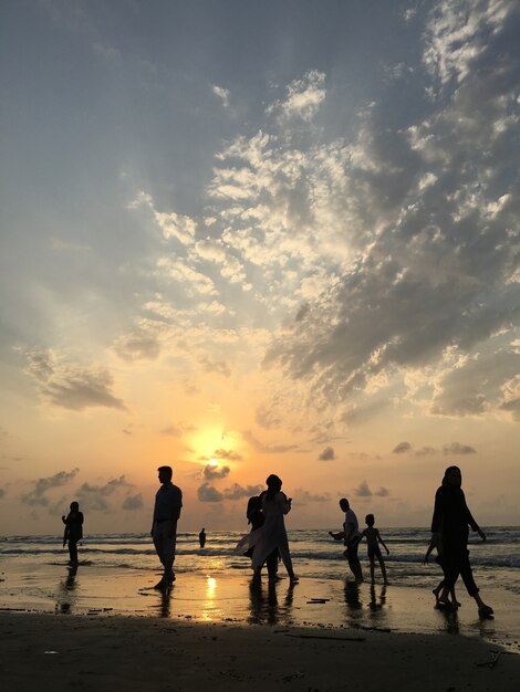 La gente sulla spiaggia del mare al tramonto divertendosi