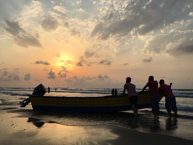 海のビーチの人々は、楽しい日没時