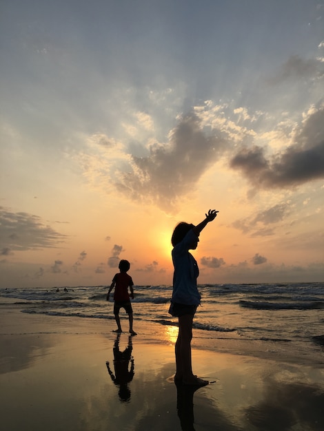 海のビーチの人々は、楽しい日没時