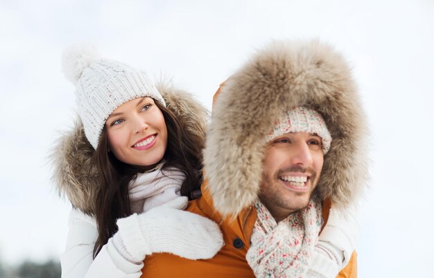 people, season, love and leisure concept - happy couple having fun over winter background