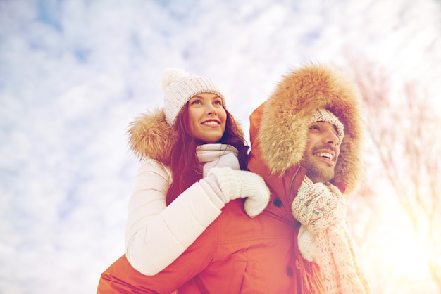 people, season, love and leisure concept - happy couple having fun over winter background