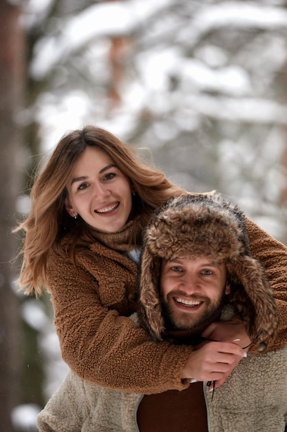 People season love and leisure concept  happy couple hugging and laughing outdoors in winter Couple embracing and having fun in snowy winter park