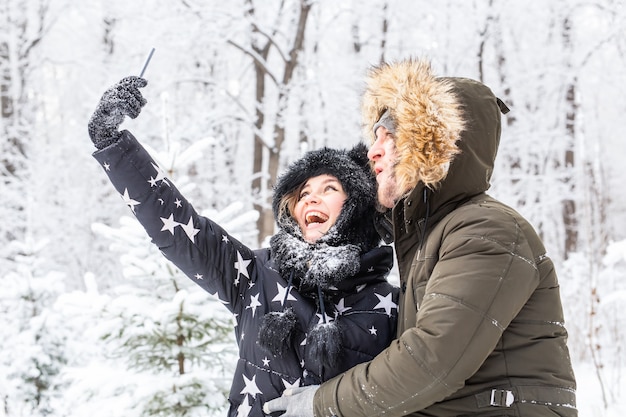 Persone, stagione, amore, tecnologia e concetto di svago - coppia felice che si fa selfie con lo smartphone su sfondo invernale