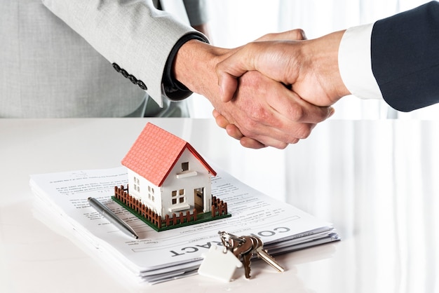 Photo people shaking hands over a toy model house