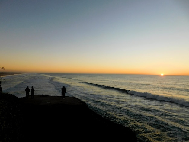 人々のシルエットはビーチで夕日を見る