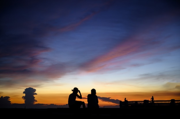 夕焼け空と海で人々のシルエット