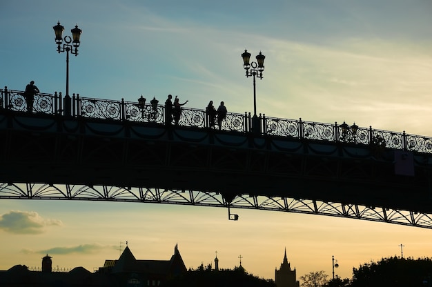 People silhouettes on a bridge at sunset