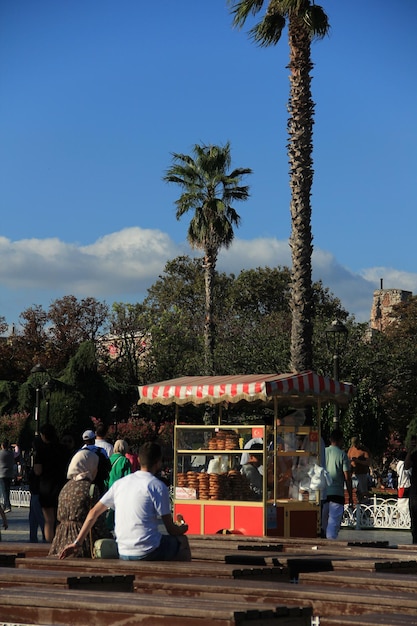 Photo people sit and rest on chairs in front of a vendor selling sesame bread photographed in istanbul in