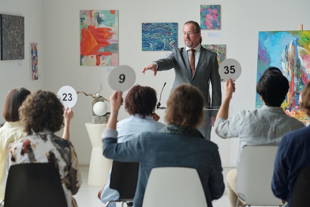 People sitting at auction in art gallery