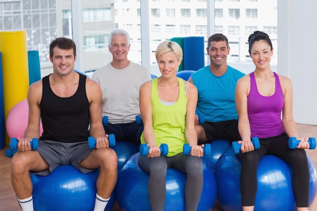 People sitting on balls and lifting weights in gym class