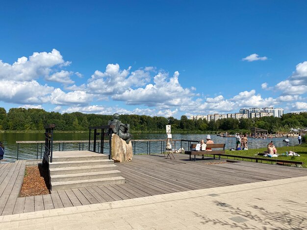 People sitting on bench by railing against sky