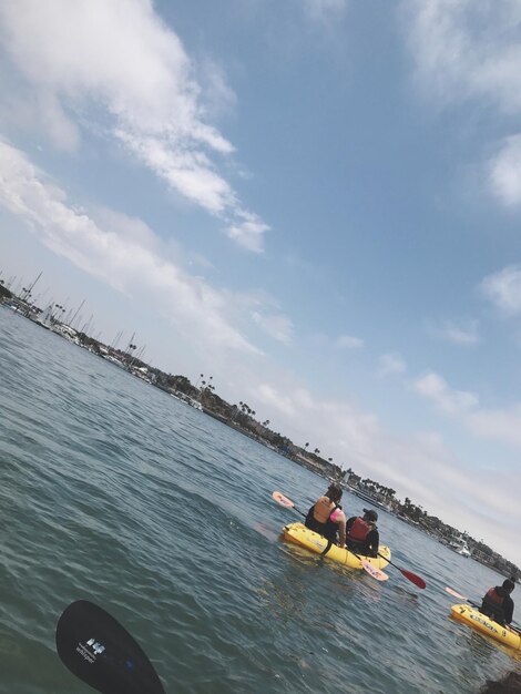 People sitting on boat in sea against sky