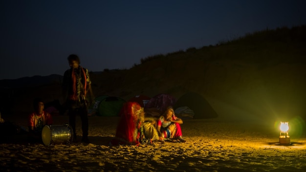 Photo people sitting by illuminated lamp on land against sky at night