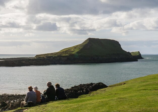 Photo people sitting by sea on hill