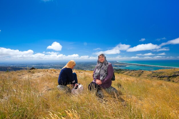 People sitting on land against sky