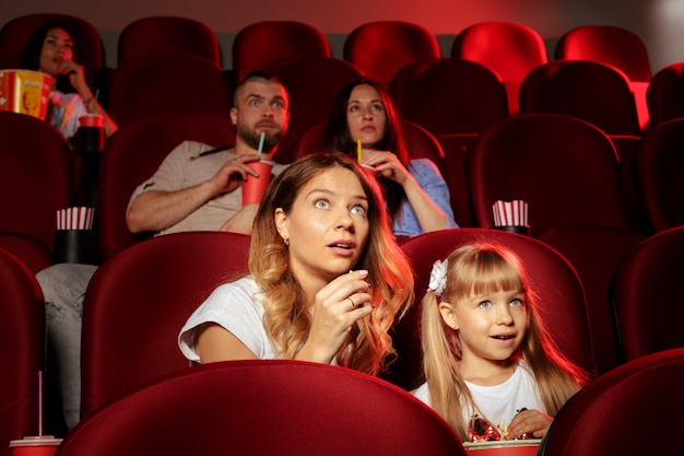 People sitting in movie theater with popcorn and drinks