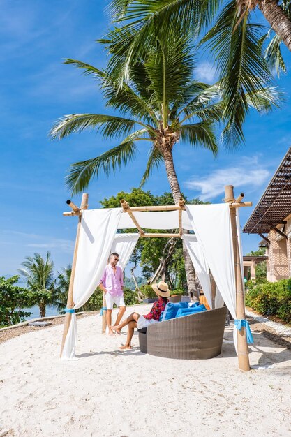 People sitting on palm tree at beach against sky