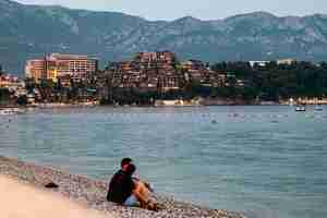 Photo people sitting and relaxing on the pebble beach and resort becici at background