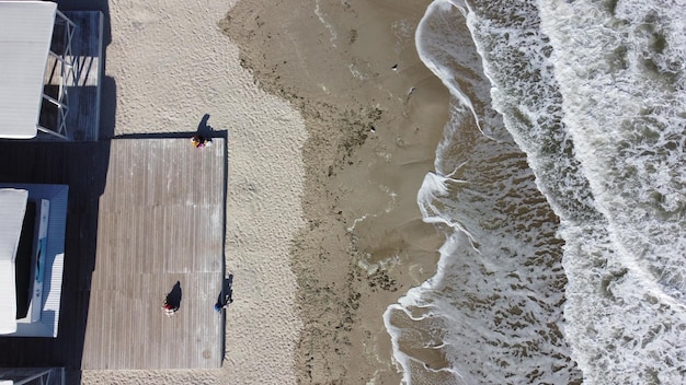 People sitting on sandy beach near sea and sea waves with white foam People rest