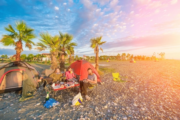 People sitting at a table near the tourist tents on the beach at sunset