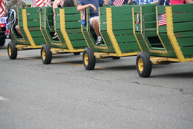 Photo people sitting in vehicle trailer on street during independence day parade