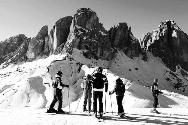Foto persone che sciano sul campo di neve da formazioni rocciose