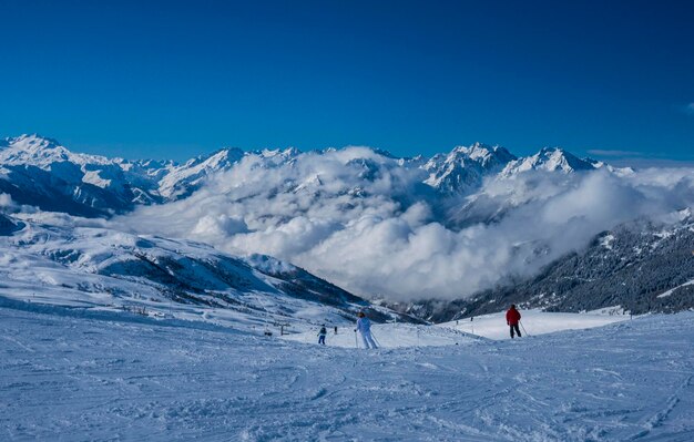 People skiing on snowcapped mountain against clear blue sky