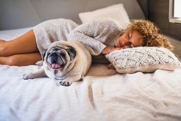 People sleeping and having relax indoor leisure activity inside camper van with her best friend pug dog on the bed Concept of love animal and friendship Healthy lifestyle woman enjoy relax