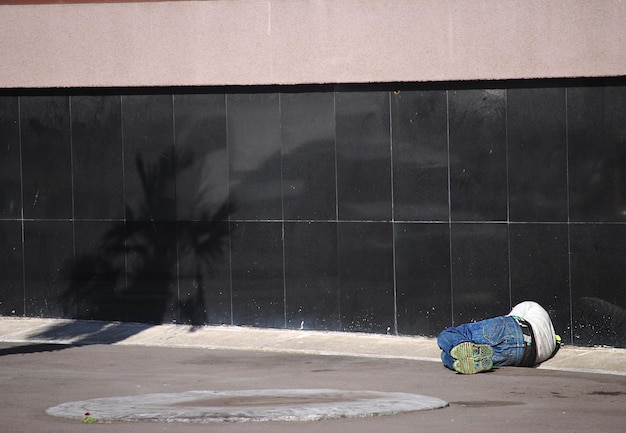 Foto gente che dorme per strada contro il muro in città