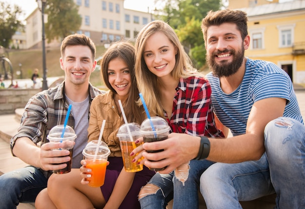 People smile and drink juice in the street together.