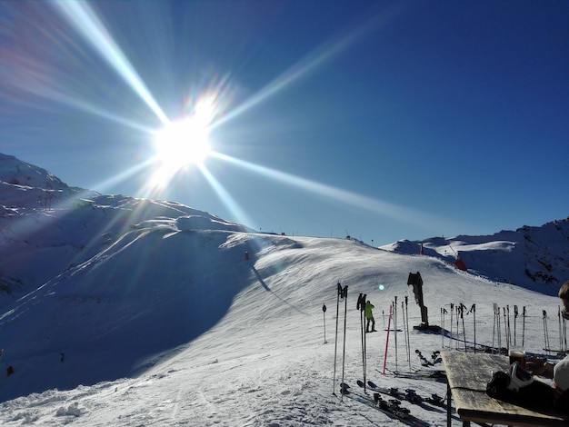 People on snowcapped mountain against clear sky during sunny day