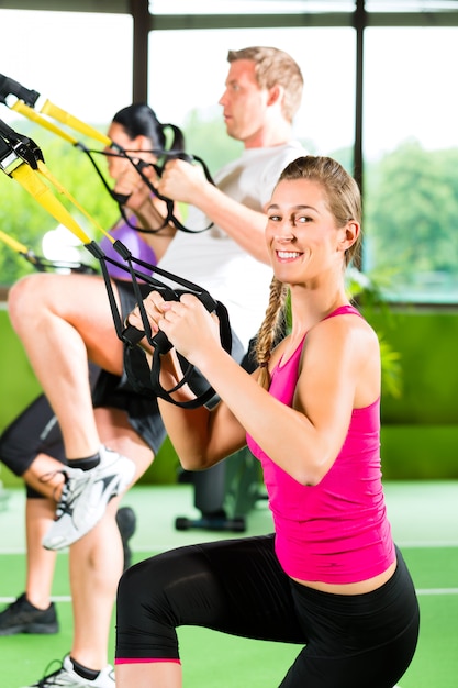 People in sport gym on suspension trainer