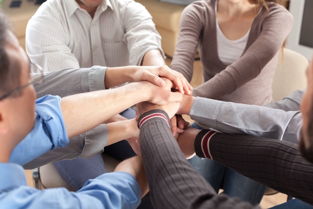 People stacking hands on light background