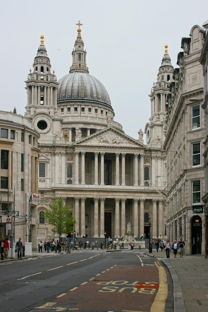 People stand in front of St Paul's Cathedral at the statue of Queen Anne in central London