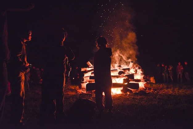 Photo people standing around bonfire at night