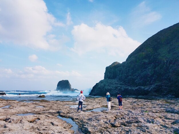 People standing at beach against sky