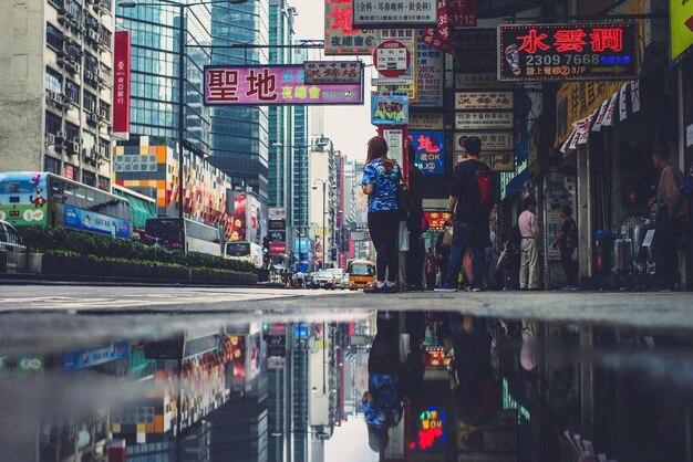 People standing by puddle on street in city