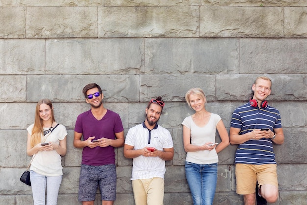 People standing in front of a wall with their phones